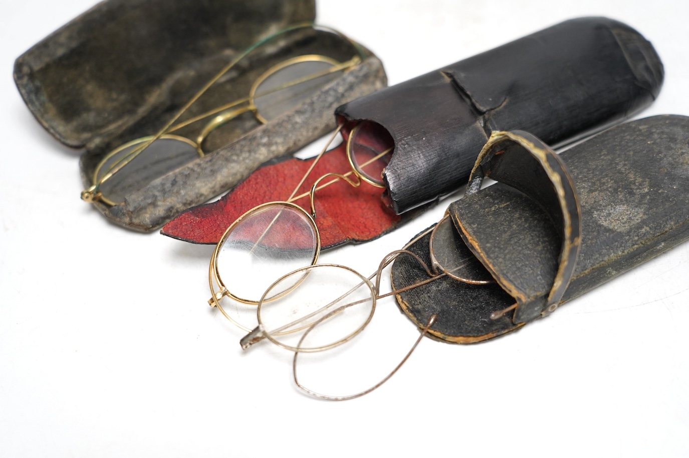 A late 19th century student’s field microscope, 22cm, and three pairs of early 20th century wire framed spectacles in contemporary cases. Condition - fair